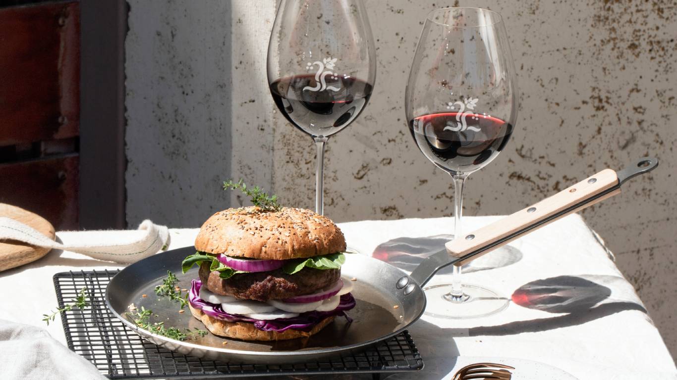 Two glasses of red wine and a burger in the sunshine to show Rioja wine and food pairing