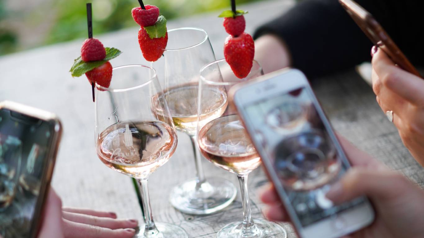 Three friends taking photos of their rose wine that shows a new Bordeaux wine style